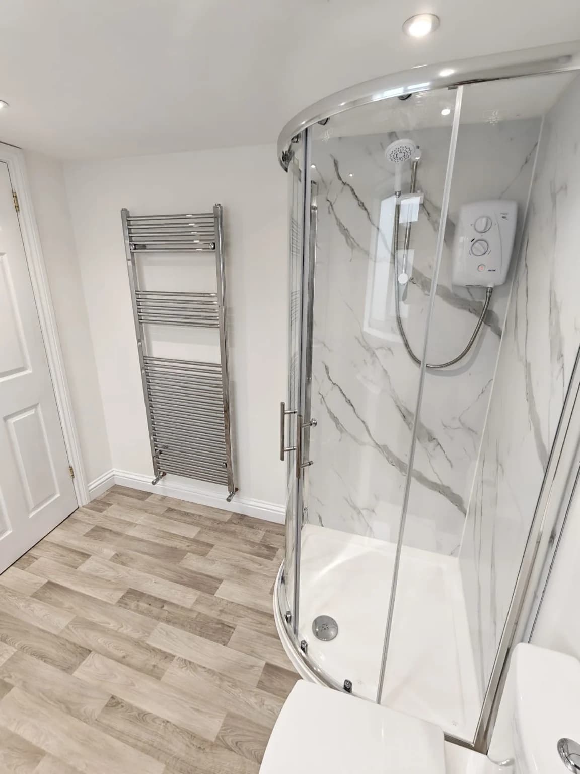 Corner shower and chrome towel radiator in the completed shower room