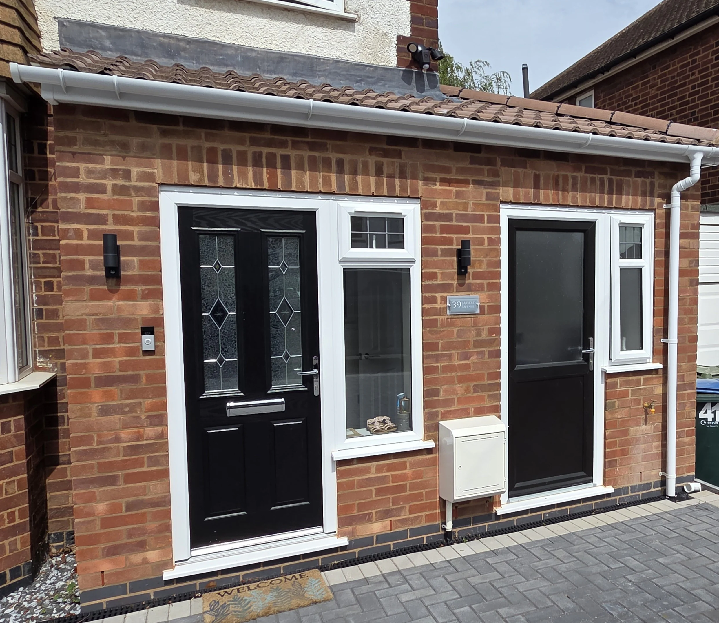 Completed red-brick Arnold Avenue side extension with two black entrance doors in Coventry