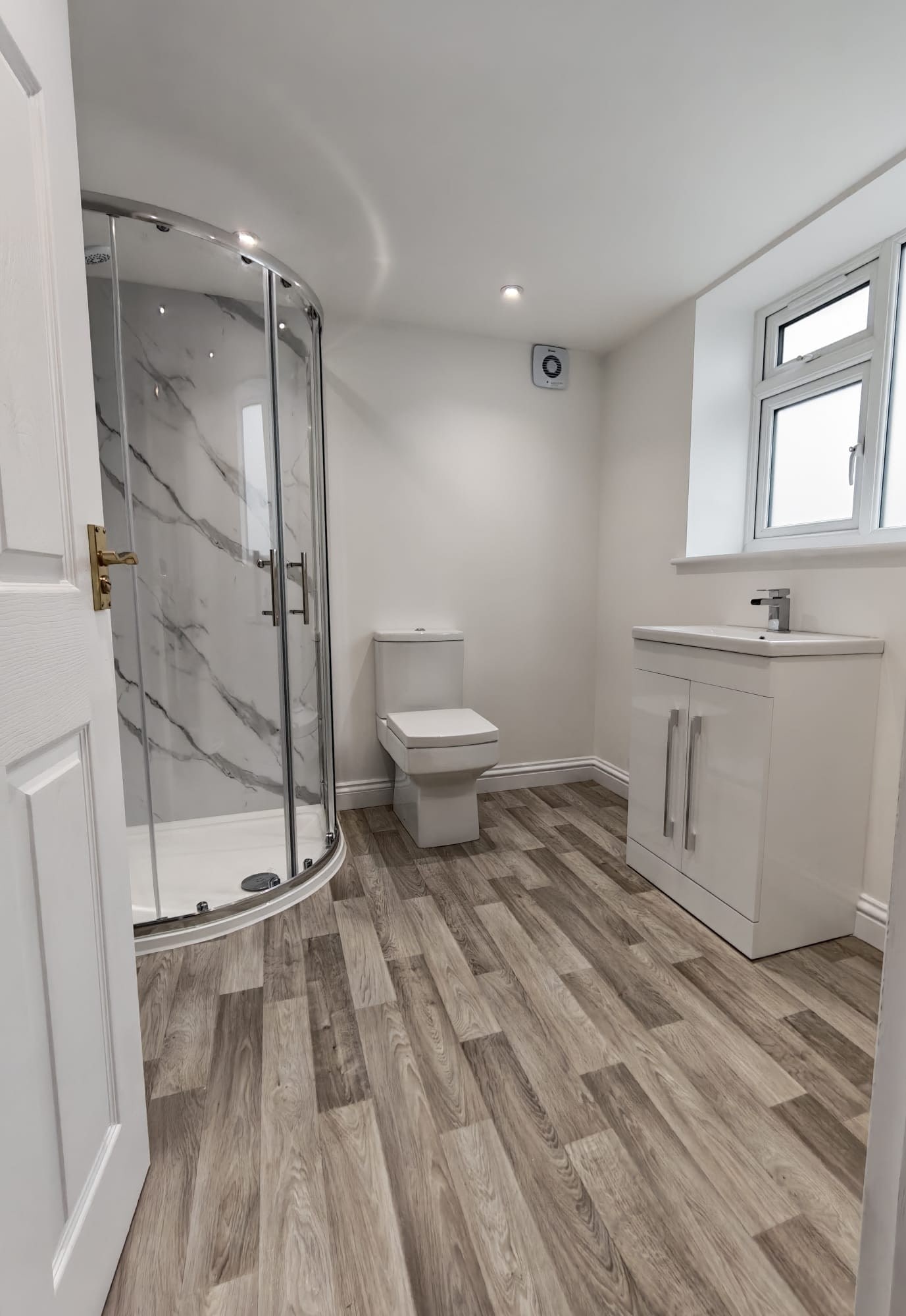 Completed shower room with a curved enclosure, toilet and vanity unit
