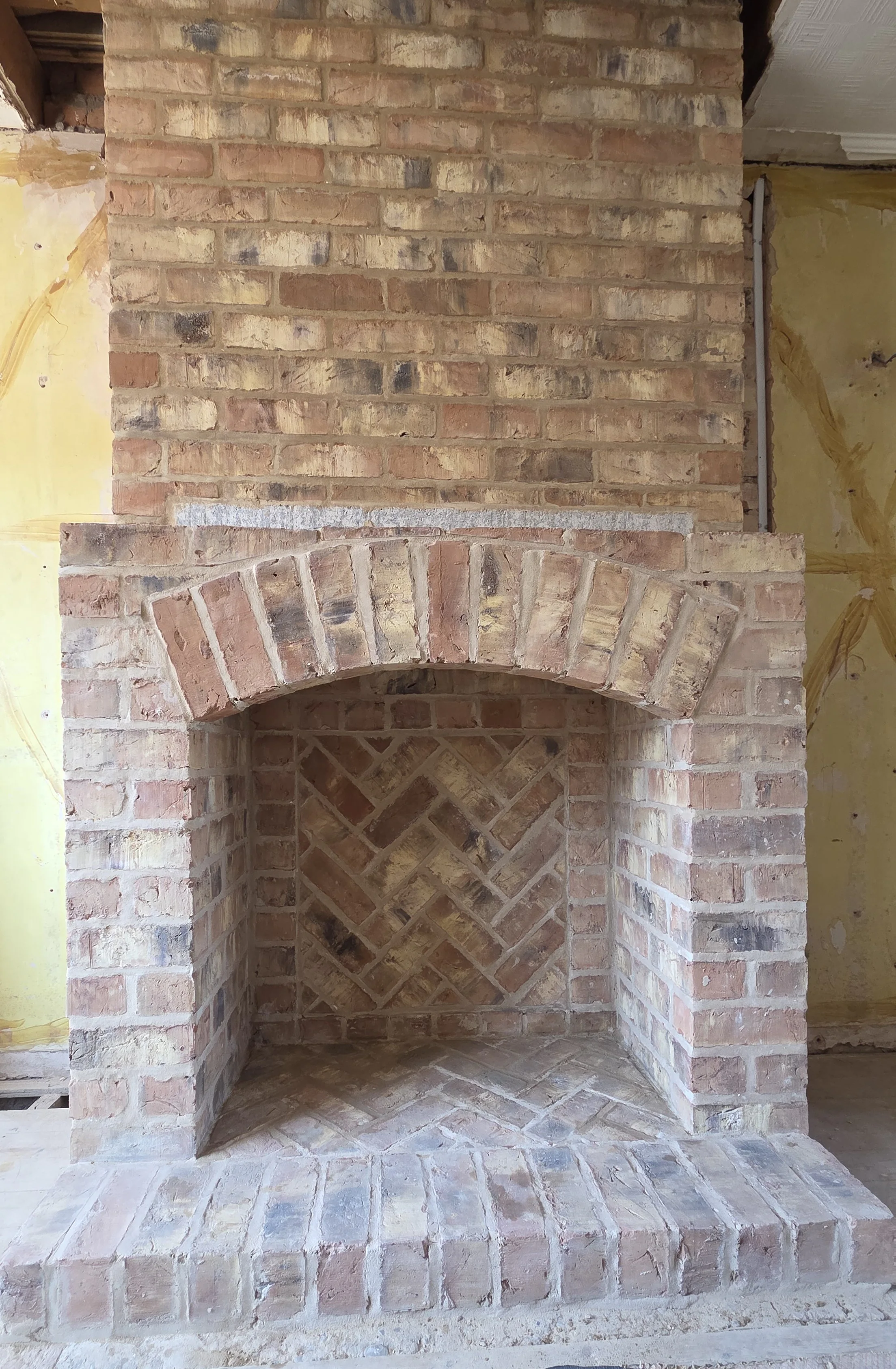 Hand-built brick fireplace with an arched opening and herringbone brickwork