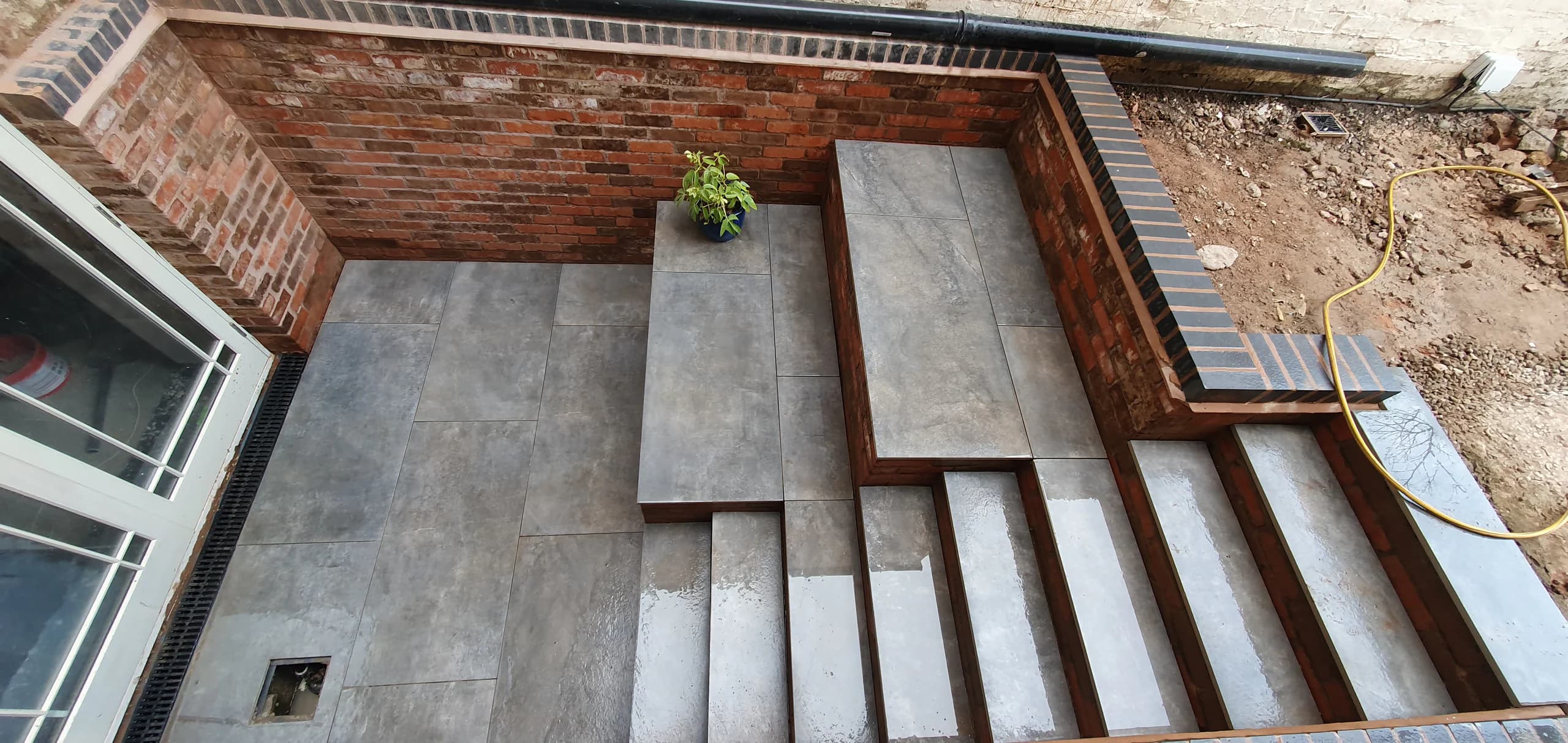 Paved courtyard and steps with brick retaining walls in Leamington Spa